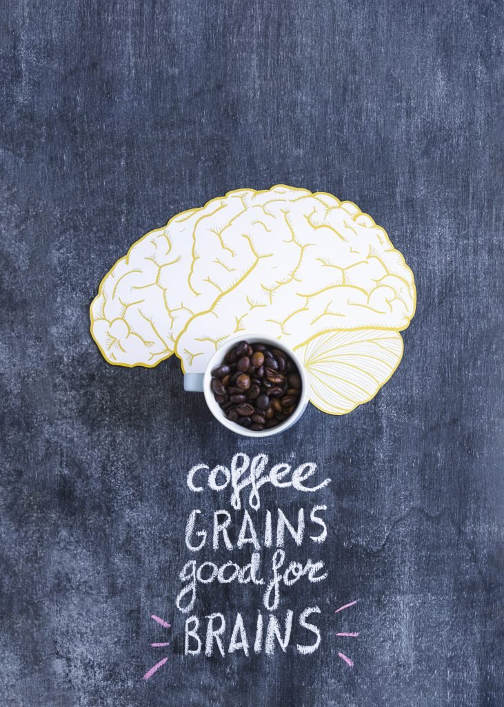 granos-cafe-tostados-taza-cerebro-recorte-papel-texto-pizarra granos de café sobre cerebro dibujado con leyenda coffe grains good for brains